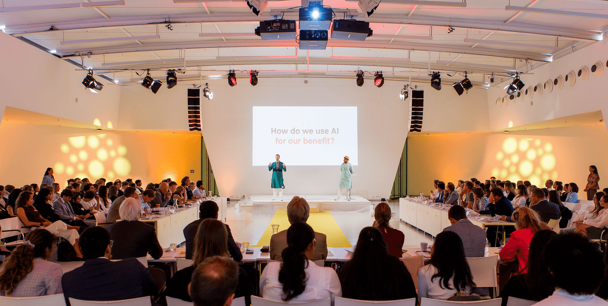 SimpleAI workshop venue, attendees seated facing the stage where the presenters are speaking.